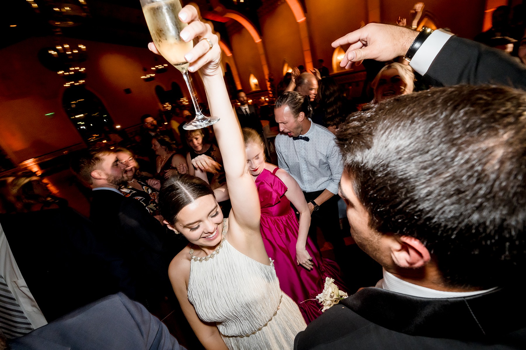 Bride dancing holding glass of champagne above her head 