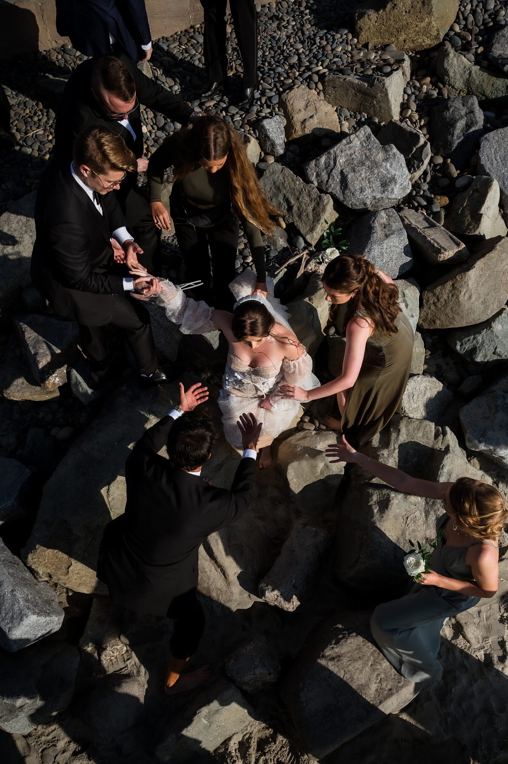 Bride being helped down the rocks to her beach wedding ceremony Southern California Wedding Photos
