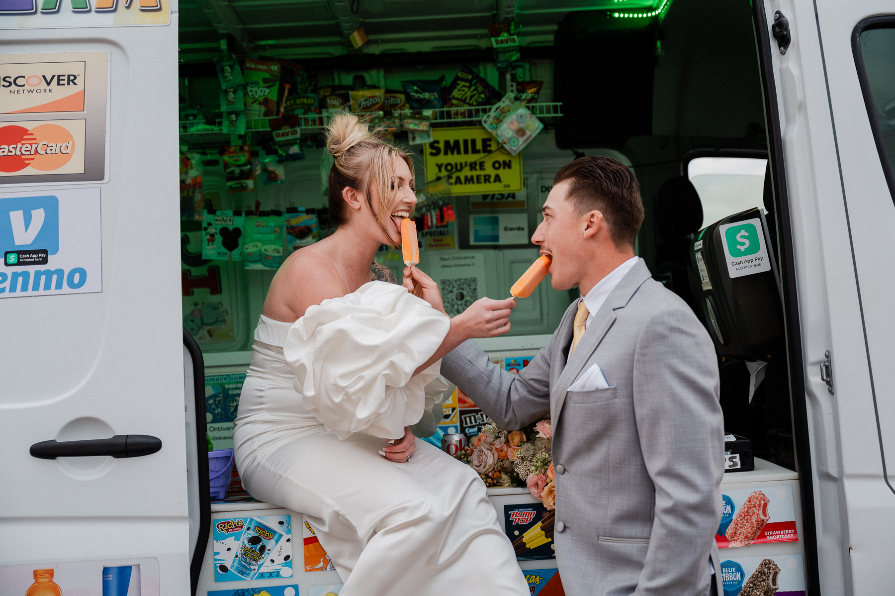 Wedding couple eating popsicles out of an ice cream truck 
