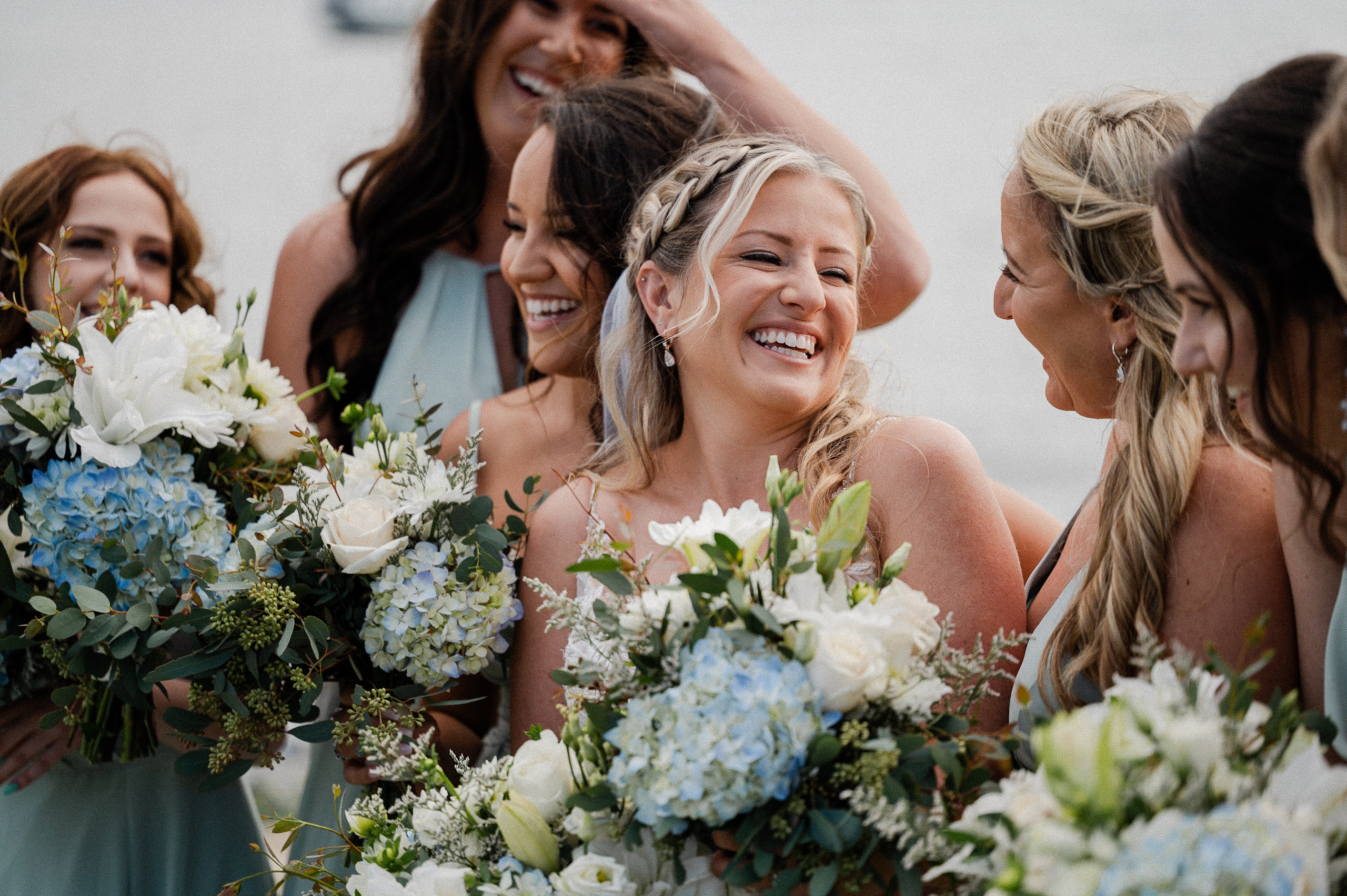 Bridesmaids in San Diego wedding holding blue flowers and laughing